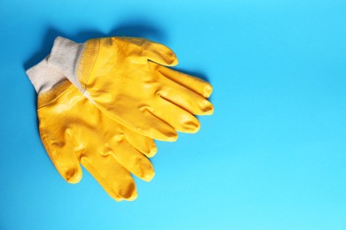 Gardening gloves on light blue background, top view. Space for text