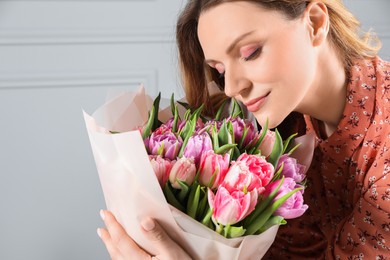 Young woman with bouquet of beautiful tulips indoors, closeup