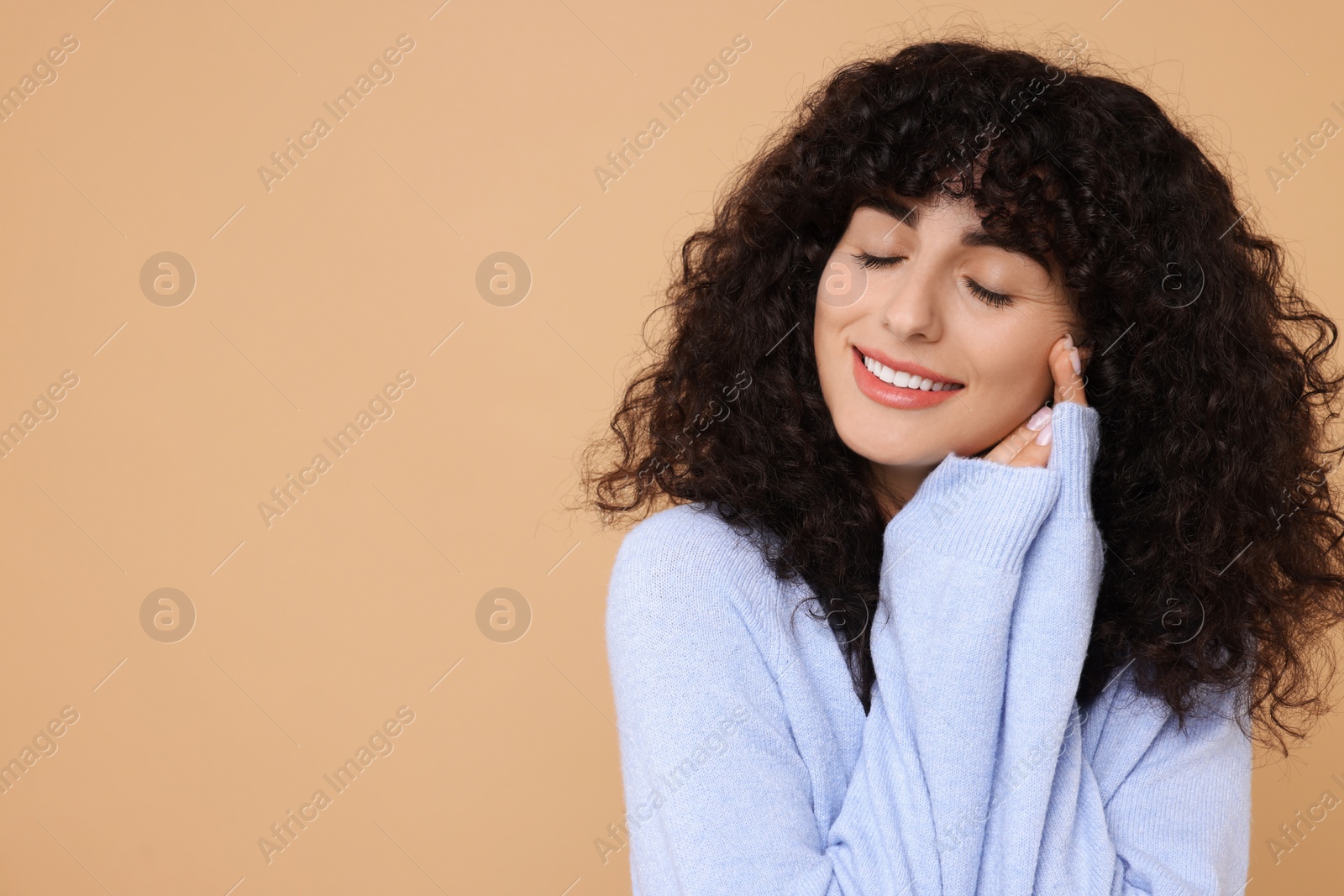 Photo of Happy young woman in stylish light blue sweater on beige background, space for text