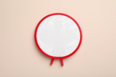 Photo of Embroidery hoop with fabric on beige background, top view