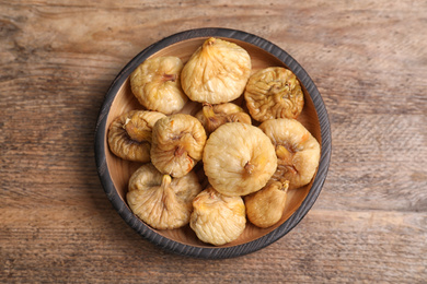 Photo of Tasty dried figs in plate on wooden table, top view