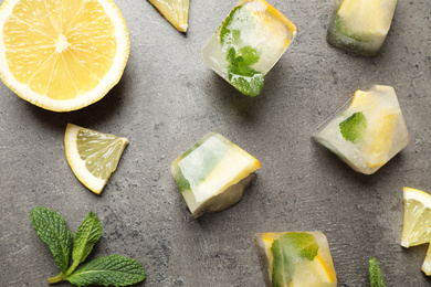 Flat lay composition with fresh juicy lemon, mint and ice cubes on grey table