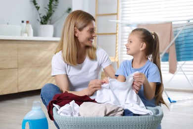 Mother and daughter taking out dirty clothes from basket in bathroom