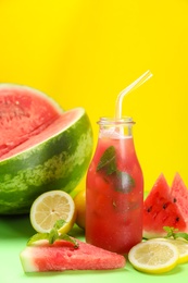 Photo of Tasty watermelon drink and fresh fruits on green table against yellow background