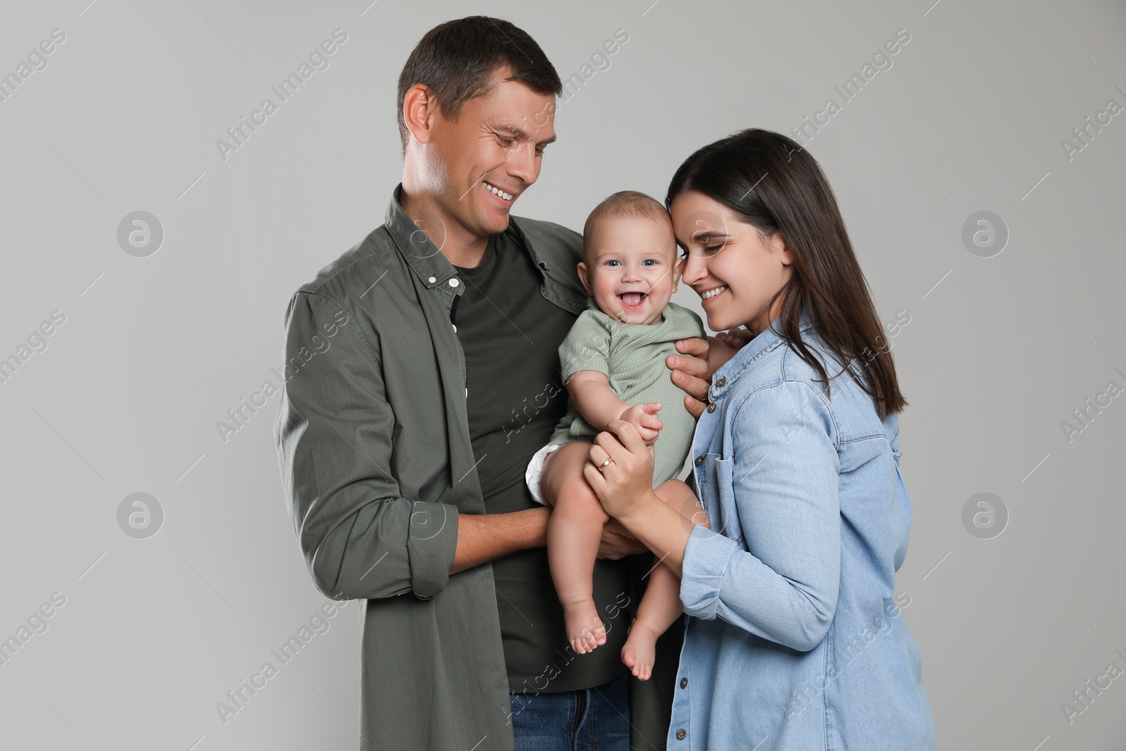 Photo of Happy family. Couple with their cute baby on grey background