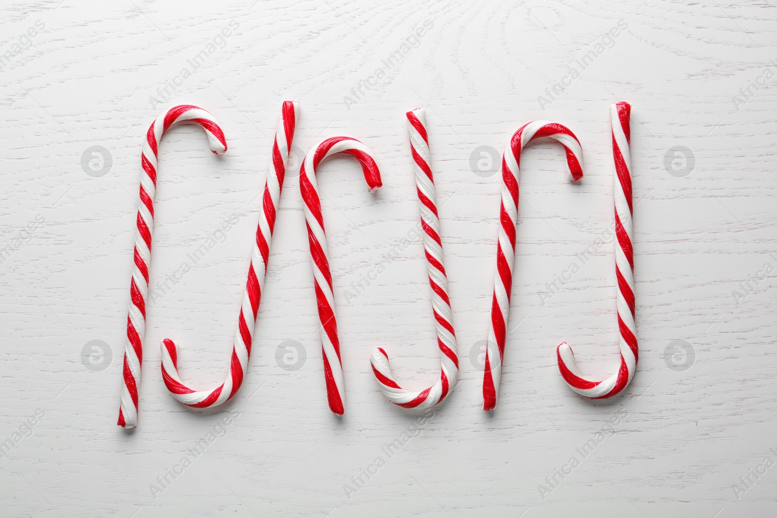 Photo of Candy canes on white wooden background, flat lay. Traditional Christmas treat