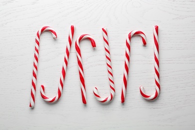Photo of Candy canes on white wooden background, flat lay. Traditional Christmas treat