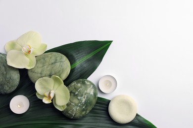 Photo of Flat lay composition with spa stones, solid shampoo bar and beautiful flowers on white table. Space for text