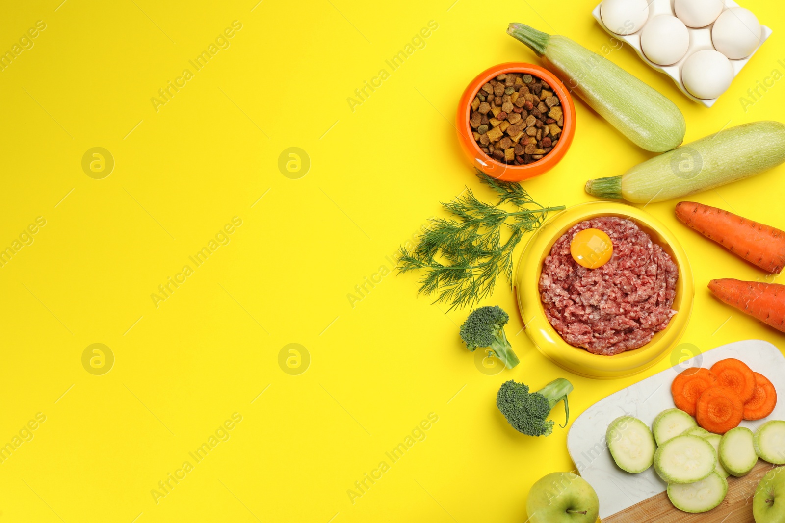 Photo of Pet food and natural ingredients on yellow background, flat lay. Space for text