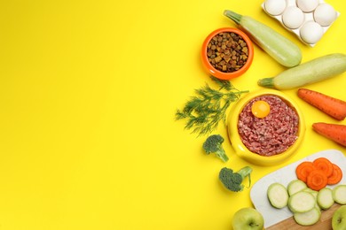 Pet food and natural ingredients on yellow background, flat lay. Space for text