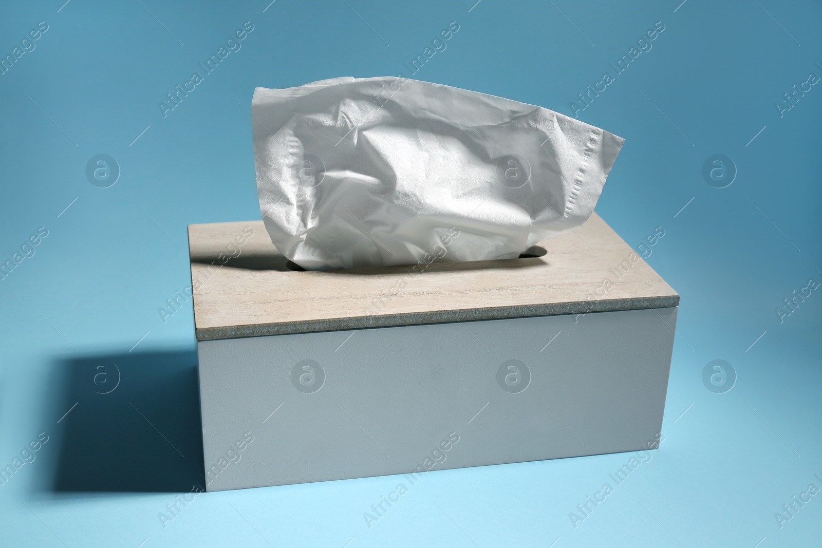 Photo of Holder with paper tissues on light blue background