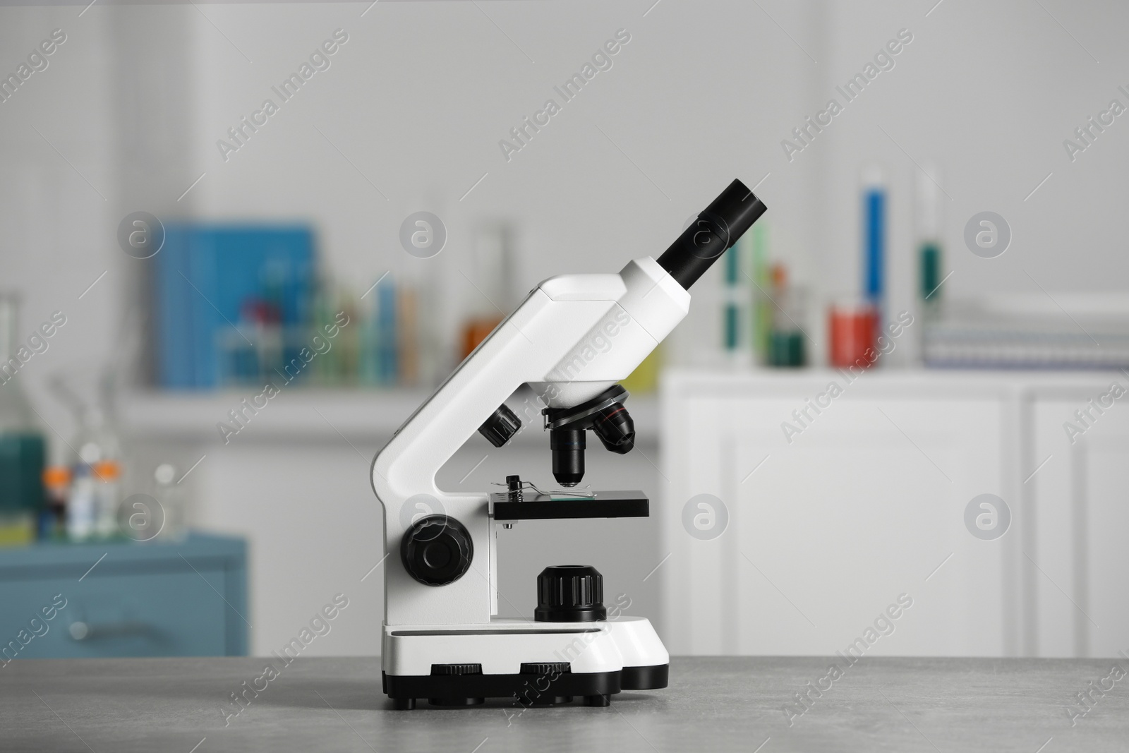 Photo of Modern medical microscope on grey table in laboratory