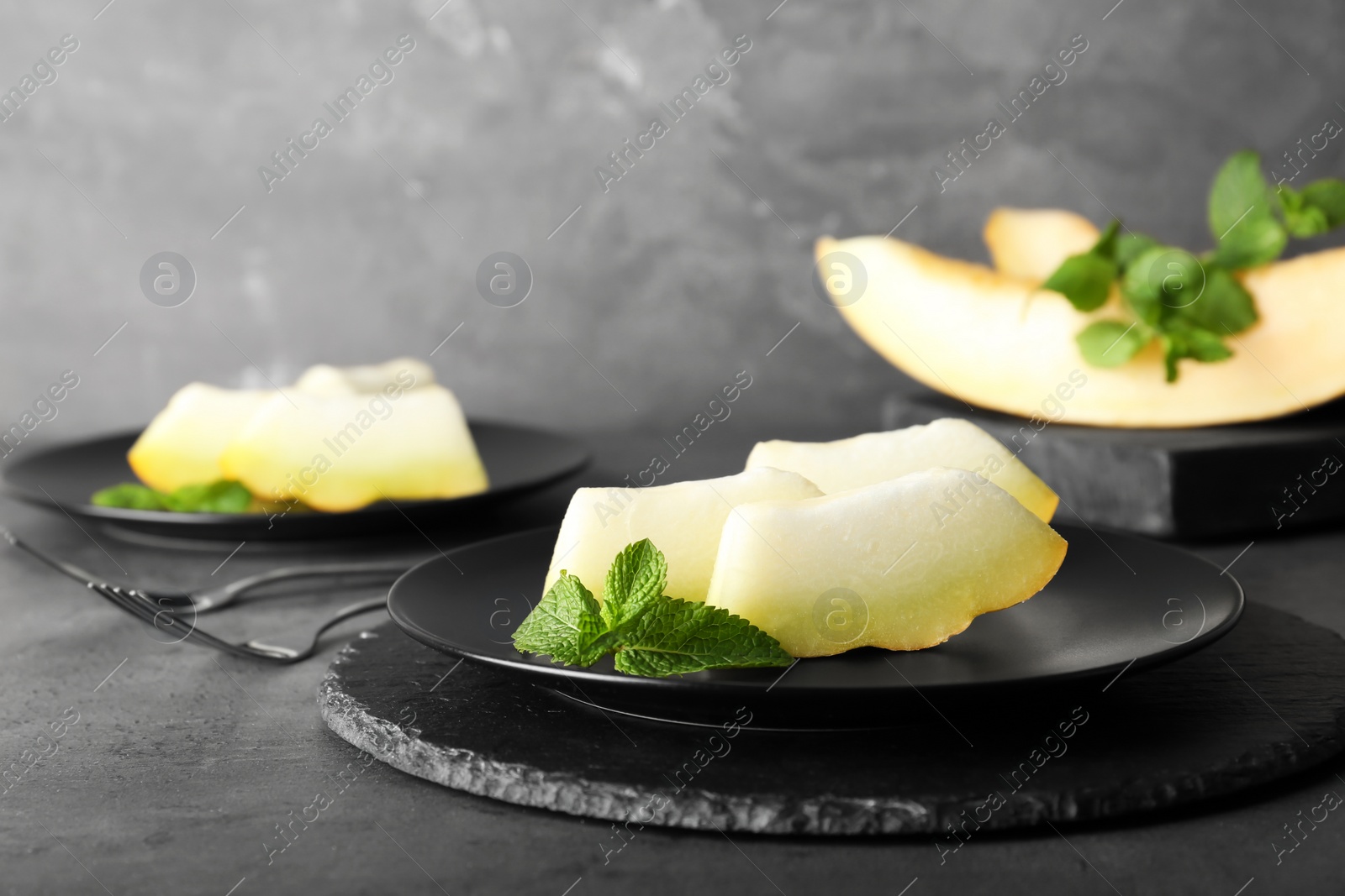 Photo of Slices of fresh ripe melon on table against gray background