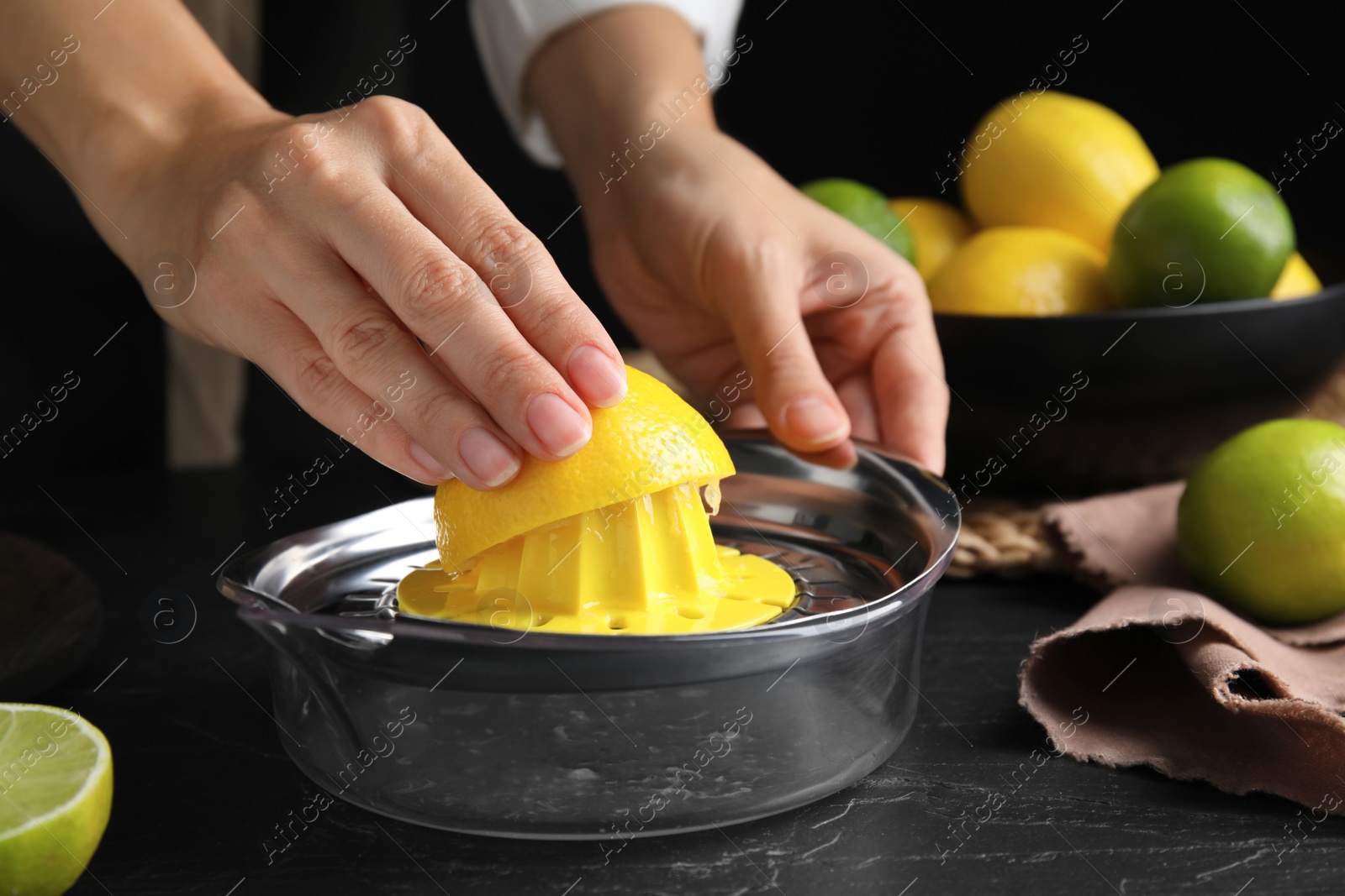 Photo of Woman squeezing lemon juice at black table, closeup