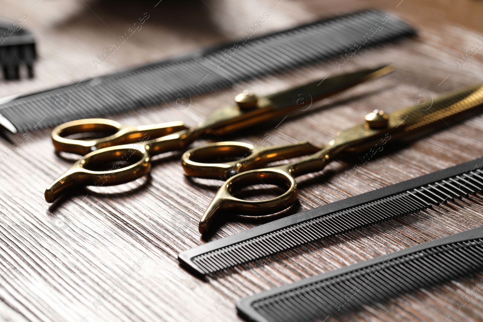 Photo of Hairdresser tools. Different scissors and combs on wooden table, closeup