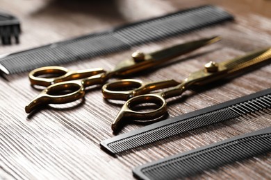 Hairdresser tools. Different scissors and combs on wooden table, closeup