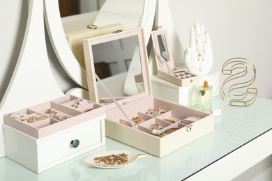 Elegant jewelry boxes with beautiful bijouterie, luxury perfume and stylish accessories on dressing table