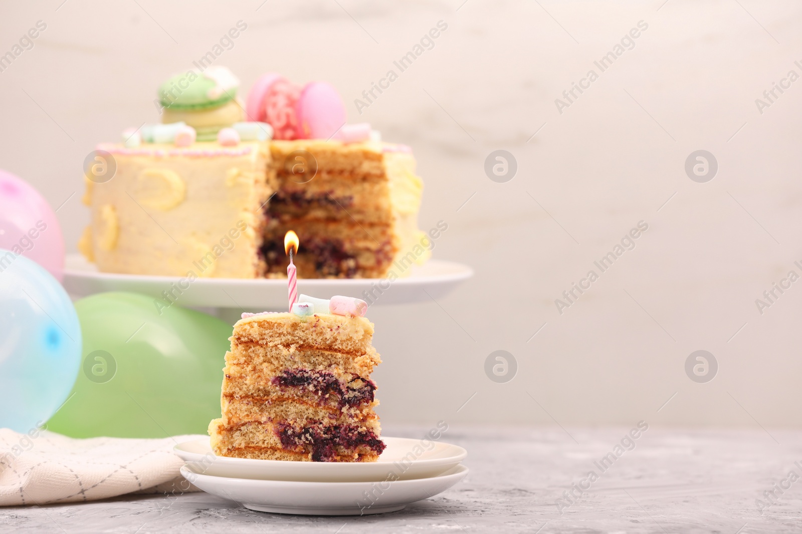 Photo of Piece of delicious cake with burning candle on light grey table, space for text
