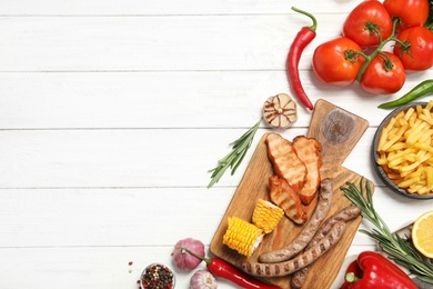 Photo of Flat lay composition with barbecued meat and vegetables on white wooden table. Space for text