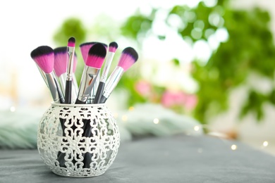 Makeup brushes in holder on blurred background