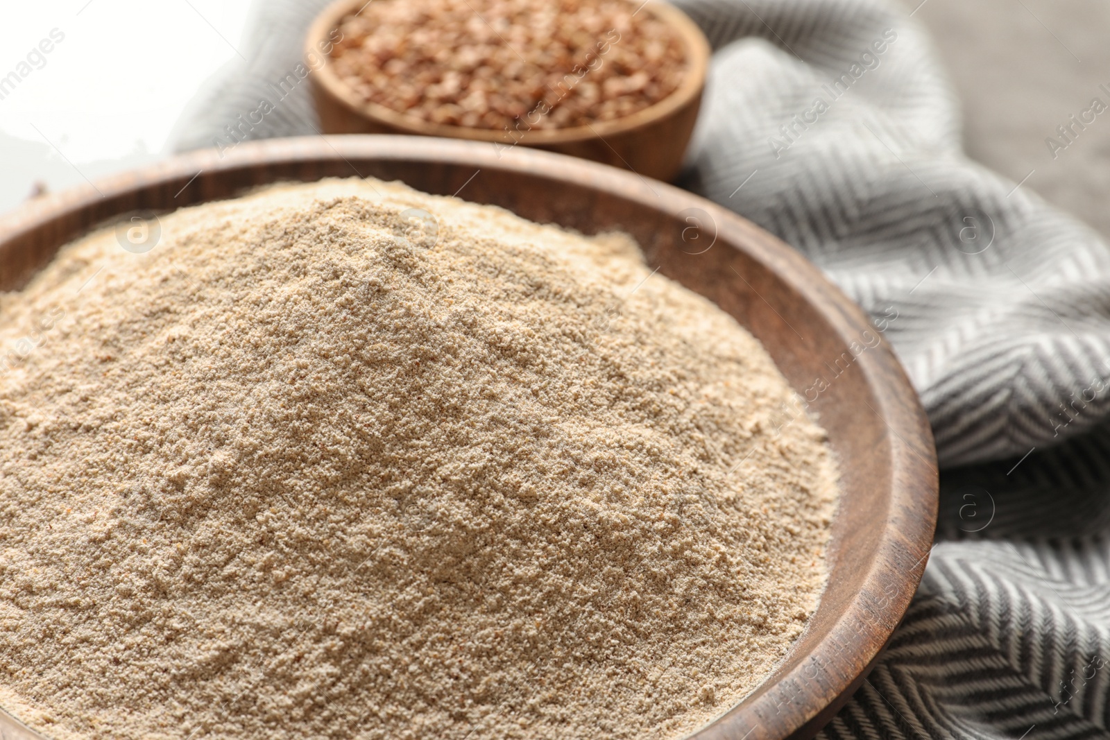 Image of Buckwheat flour in wooden bowl on table, closeup