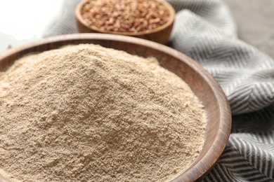 Buckwheat flour in wooden bowl on table, closeup