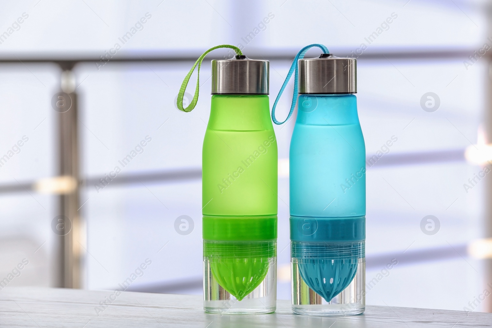 Photo of Sports water bottles on table against blurred background. Space for text