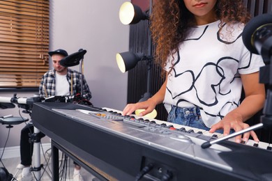African American woman playing synthesizer during studio rehearsal, closeup. Music band practice
