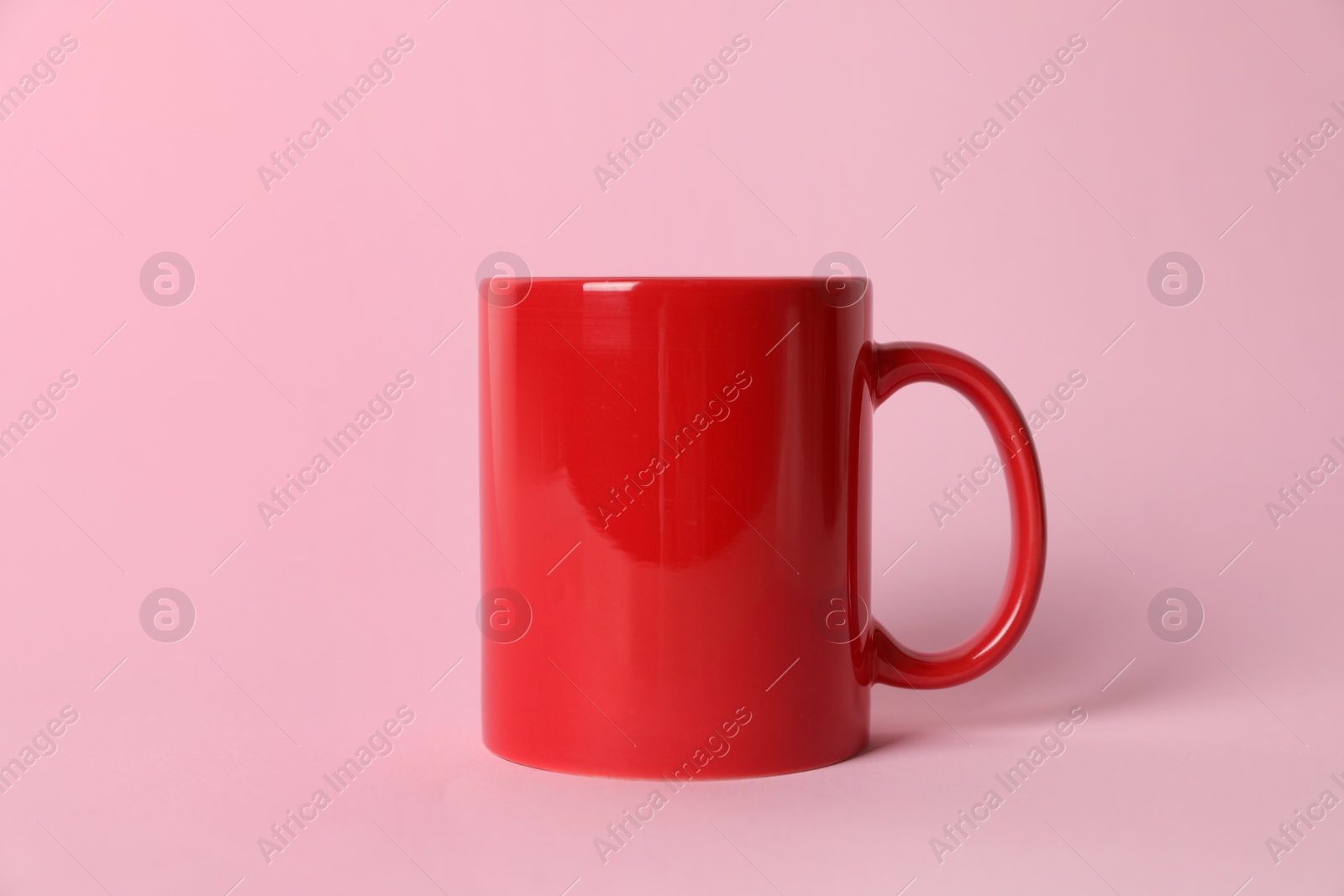 One red ceramic mug on pink background Photo of One red ceramic mug on pink background