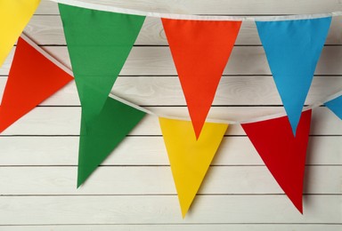 Photo of Buntings with colorful triangular flags on white wooden background