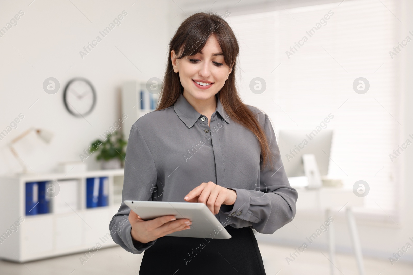 Photo of Smiling secretary working with tablet in office