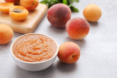 Apricot puree in bowl and fresh fruits on light grey table