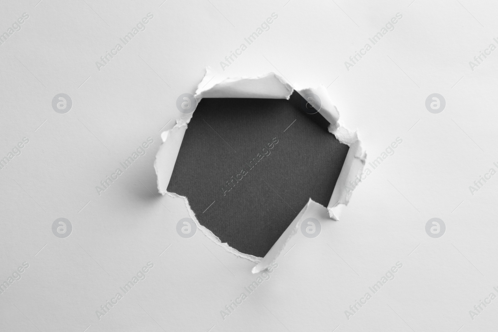 Photo of Hole in white paper on black background