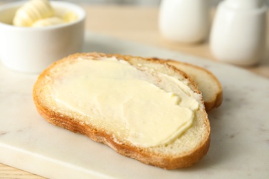 Photo of Tasty bread with butter for breakfast on marble board