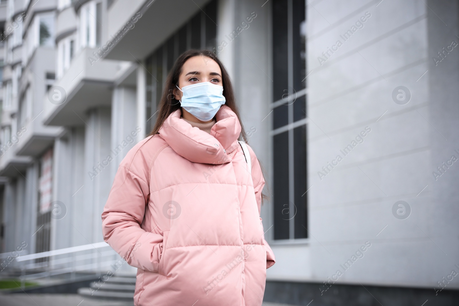 Photo of Young woman in medical face mask walking outdoors. Personal protection during COVID-19 pandemic