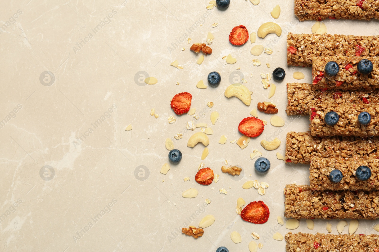 Photo of Tasty granola bars and ingredients on beige marble table, flat lay. Space for text