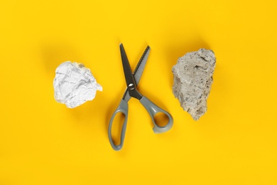 Flat lay composition with rock, paper and scissors on yellow background