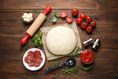 Photo of Flat lay composition with dough and fresh ingredients for pepperoni pizza on wooden table