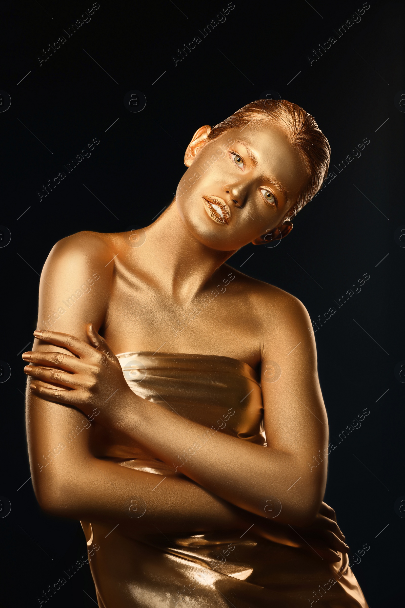 Photo of Portrait of beautiful lady with gold paint on skin against black background