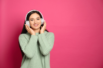 Photo of Young woman listening to audiobook on pink background. Space for text