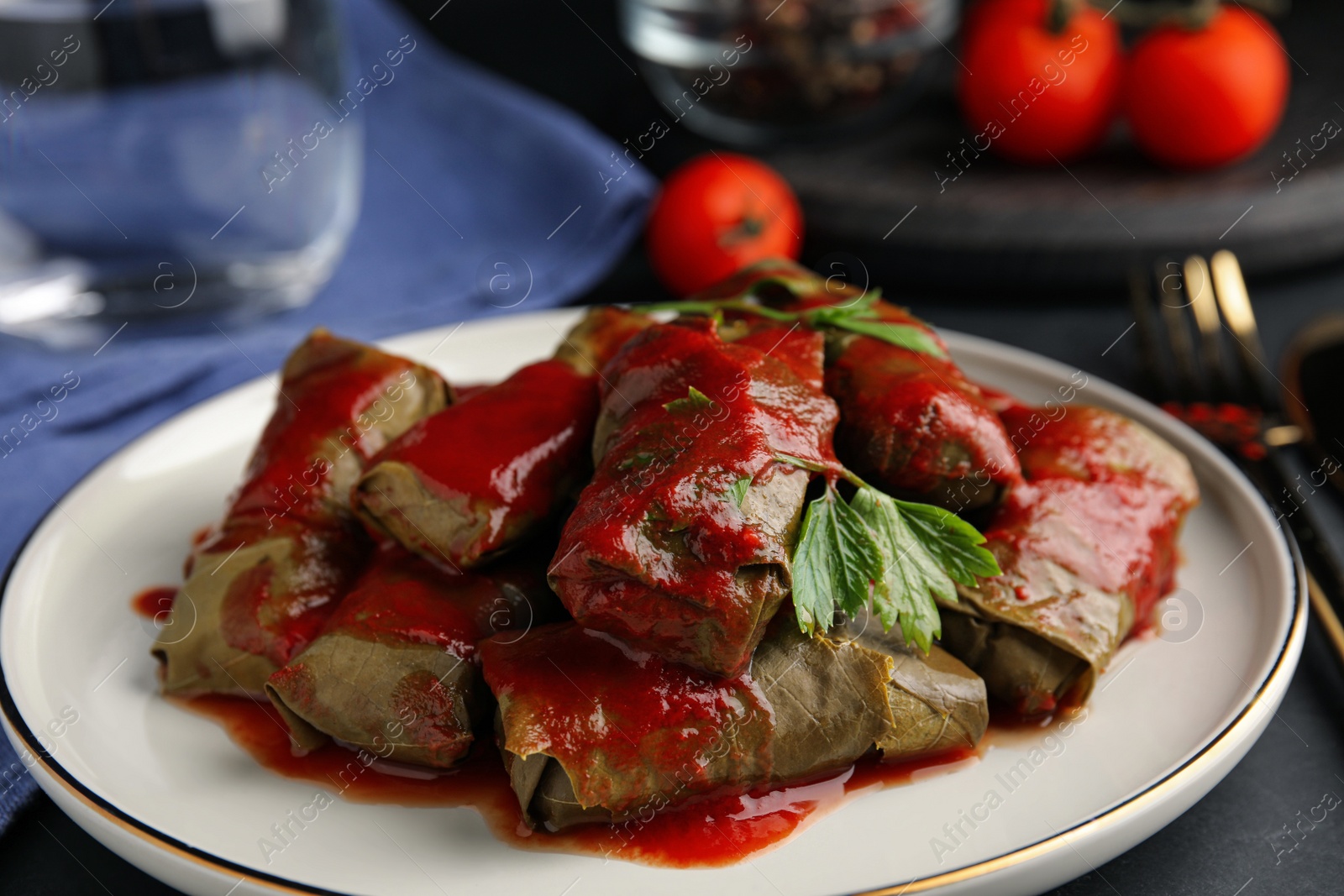 Photo of Delicious stuffed grape leaves with tomato sauce on table, closeup