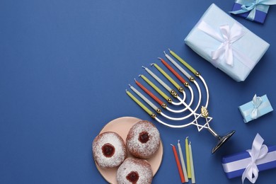 Photo of Flat lay composition with Hanukkah menorah and donuts on blue background, space for text