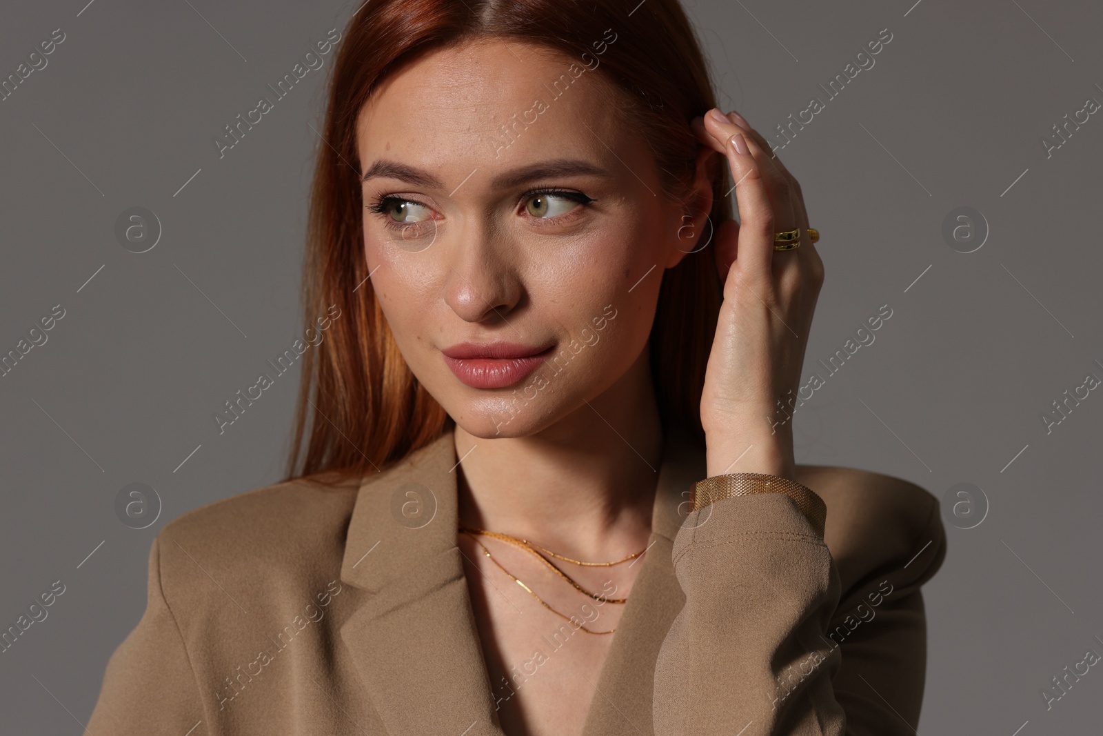 Photo of Beautiful young woman with elegant jewelry on gray background