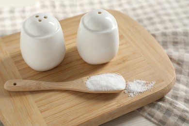 Photo of Spice shakers with salt on white table