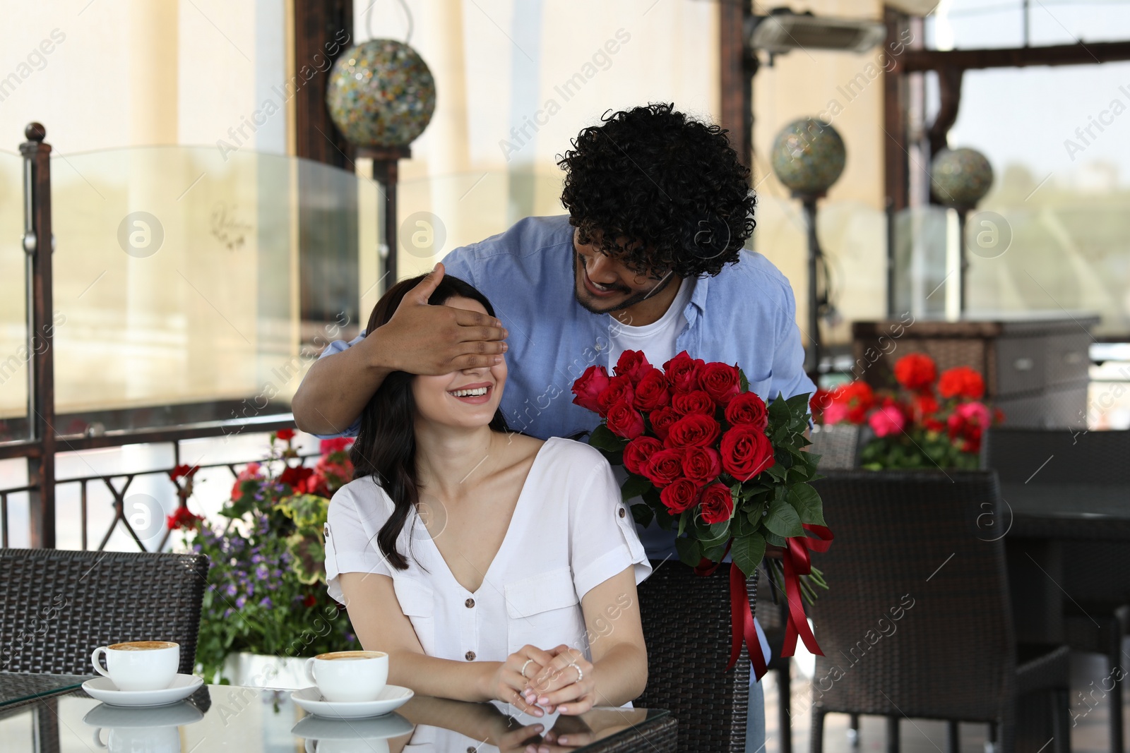 Photo of International dating. Handsome man presenting roses to his girlfriend in restaurant