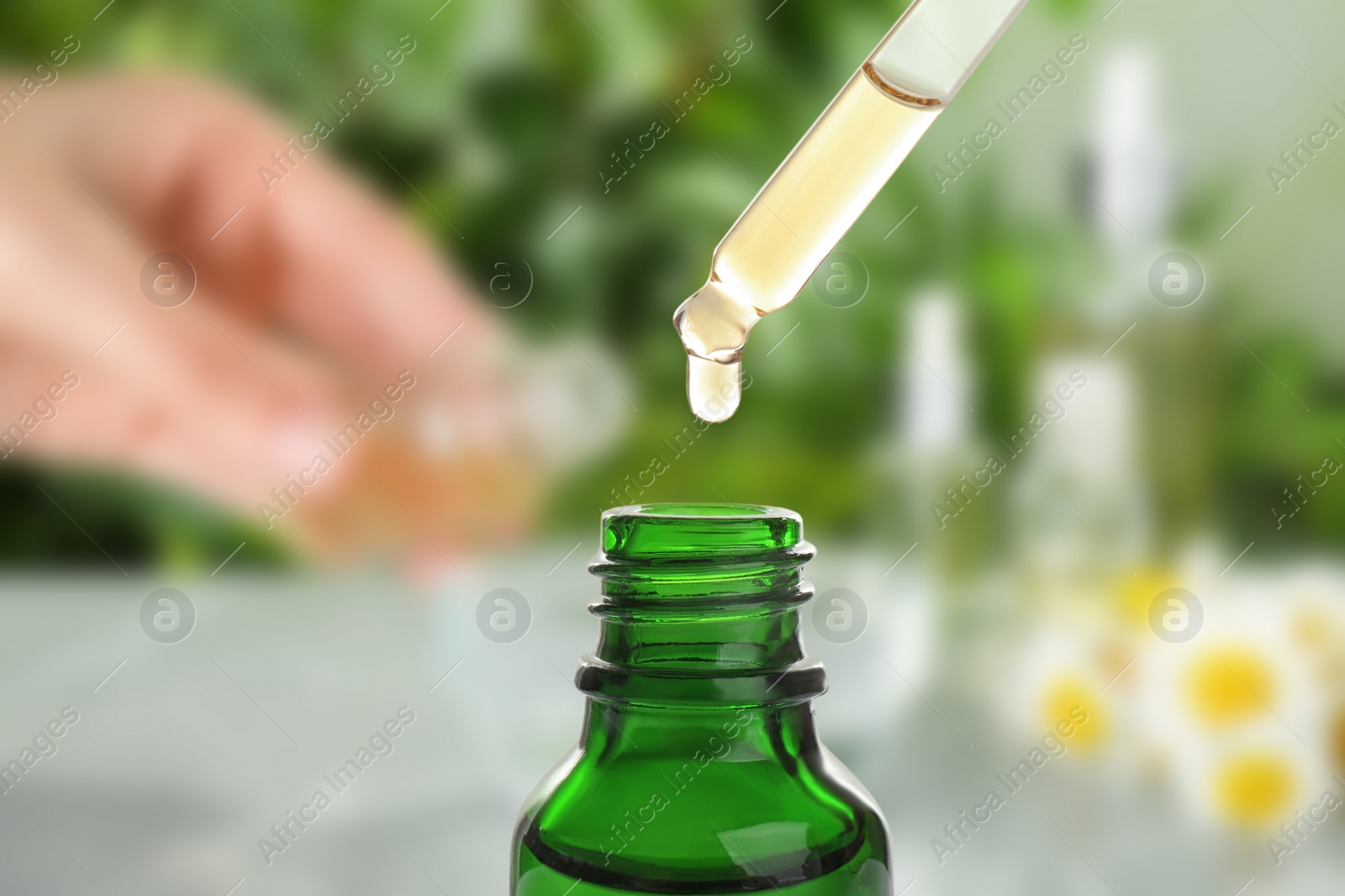 Image of Little bottle with essential oil and dropper against blurred background 