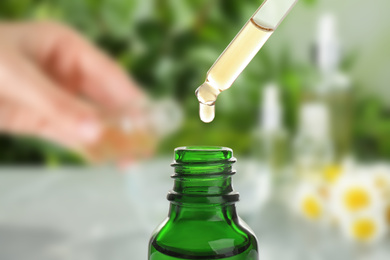 Little bottle with essential oil and dropper against blurred background 