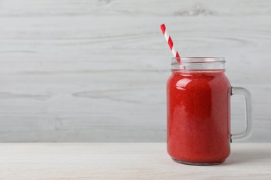 Mason jar with delicious berry smoothie on white wooden table. Space for text