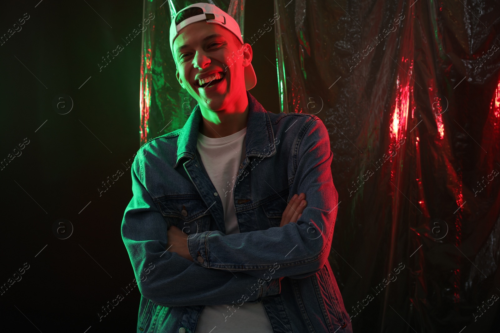 Photo of Happy young man on dark background in neon lights