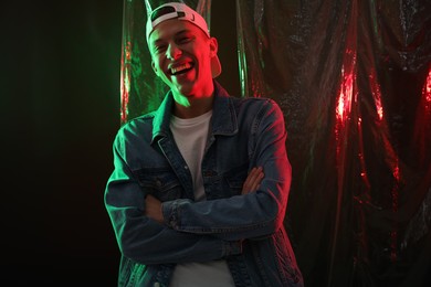 Photo of Happy young man on dark background in neon lights